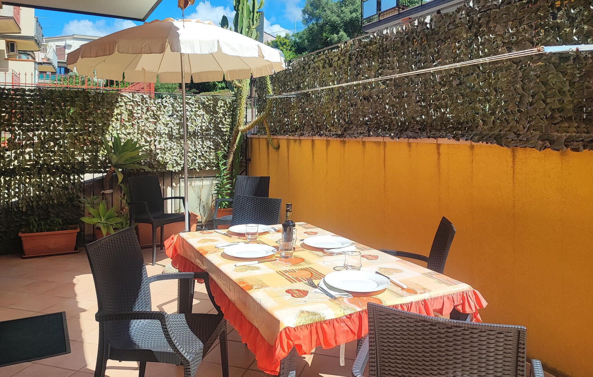 An outdoor patio with a table set for dining, surrounded by chairs and a large umbrella.