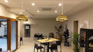 Ein moderner Hotel-Speiseraum mit einem zentralen Tisch, schwarzen Stühlen und zwei goldenen Pendelleuchten.