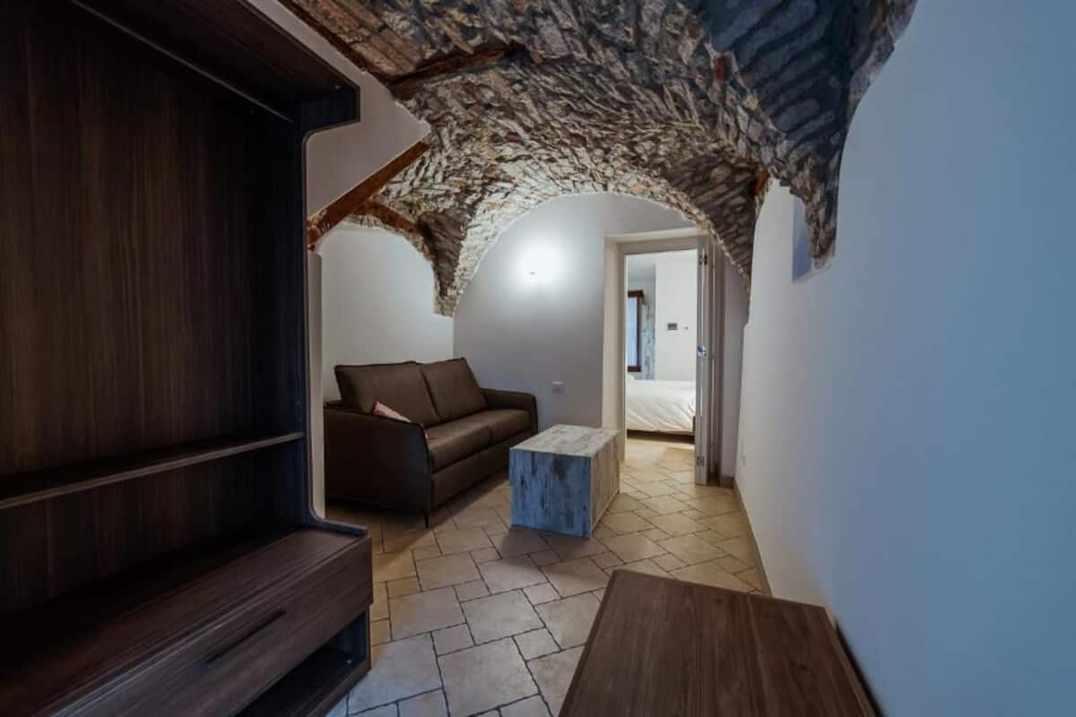 A cozy room with a stone ceiling, a brown sofa, a small wooden table, and a tiled floor.