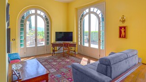 A room with two arched windows, a television, a sofa, a table, and a patterned rug.
