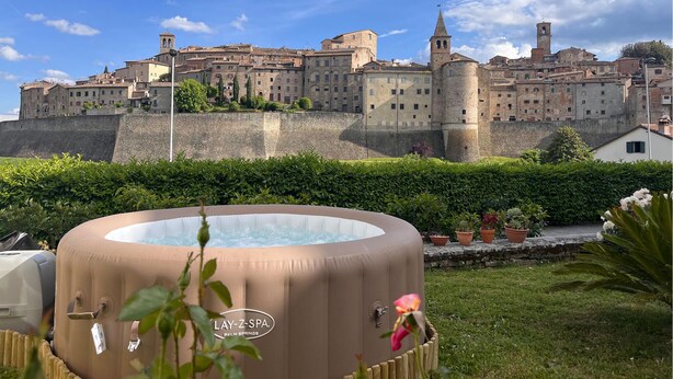 A hot tub in a garden with a historic building in the background.