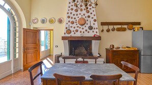 A cozy kitchen with a fireplace, wooden furniture, and a variety of hanging cookware.