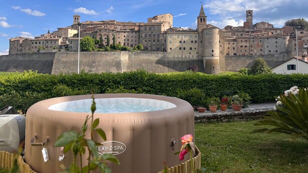 A hot tub in a garden with a historic building in the background. - Beautiful apartment in Anghiari with WiFi (Anghiari)