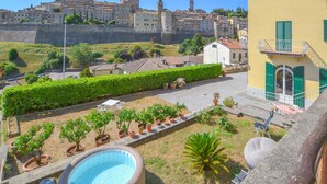 A courtyard with a swimming pool, potted plants, and a view of historic buildings in the background.