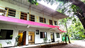 A two-story building with a red roof and multiple windows. - Lotus Cottage (Alibag)