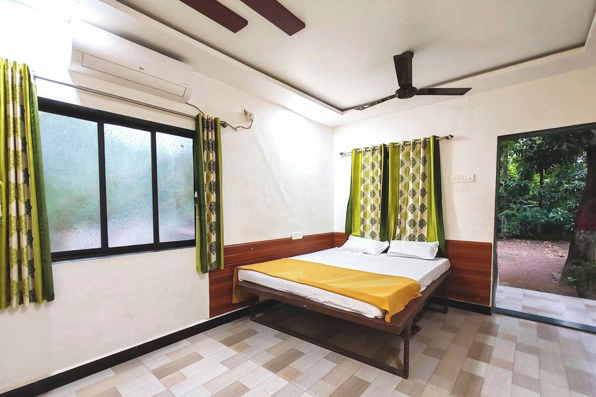 A bedroom with a bed, an air conditioning unit, a ceiling fan, and a window with curtains.