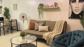 Ein Wohnzimmer mit einer Couch, einem Couchtisch, einem Ventilator und einem blauen Sessel.
