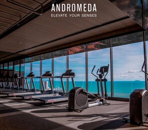 A gym with cardio equipment and a view of the ocean.