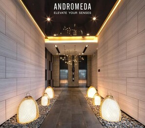 A modern hallway with a tiled floor, decorative lighting, and a central chandelier.