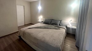 A bedroom with a bed, bedside tables, and a door.