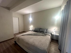 Een slaapkamer met een bed, nachtkastjes en een deur.