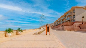 Ein modernes Hotel mit gepflastertem Weg, blauem Himmel und Blick aufs Meer.