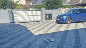 Un camino pavimentado con un coche azul estacionado a la derecha.