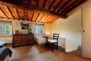 A room with a wooden ceiling, a bench, a chair, a radiator, and a window with a view of greenery. - Historic country home in Villa with Pool (Toscana)