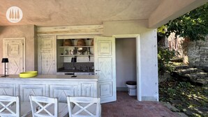 A kitchen with a bar area, white cabinetry, and a stone wall with greenery.