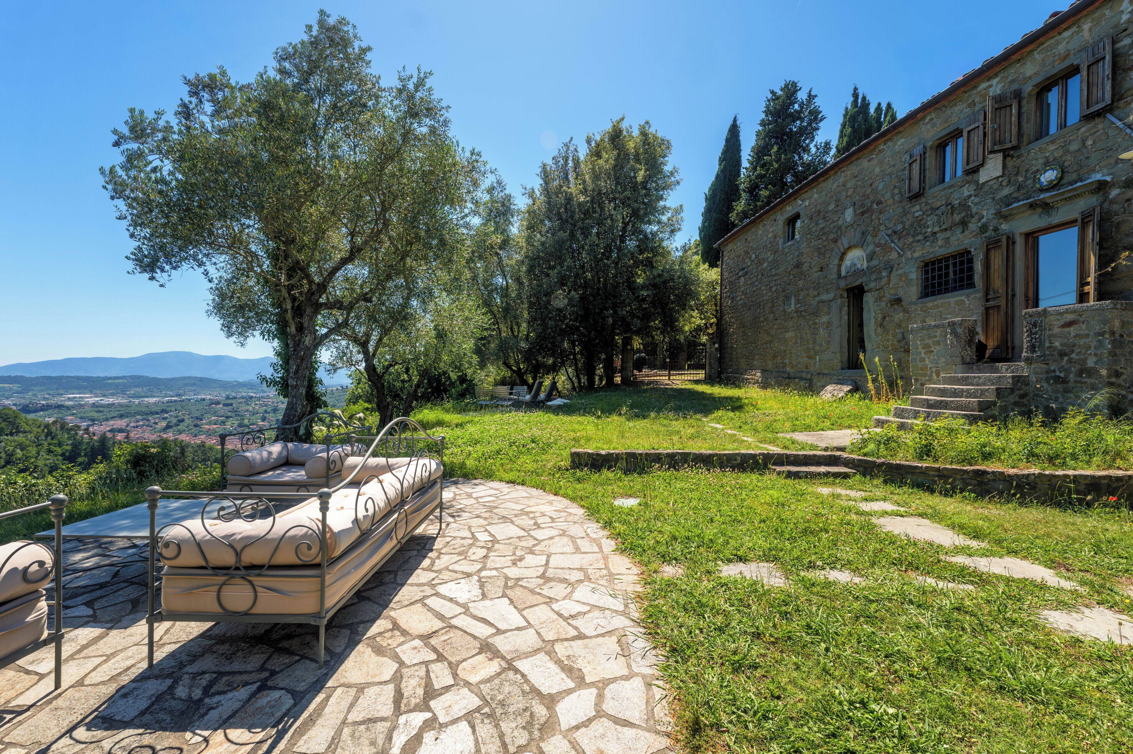 A stone pathway leading to a bed with a view of a stone building and trees.