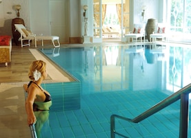Una piscina con sillones de descanso y una estatua.