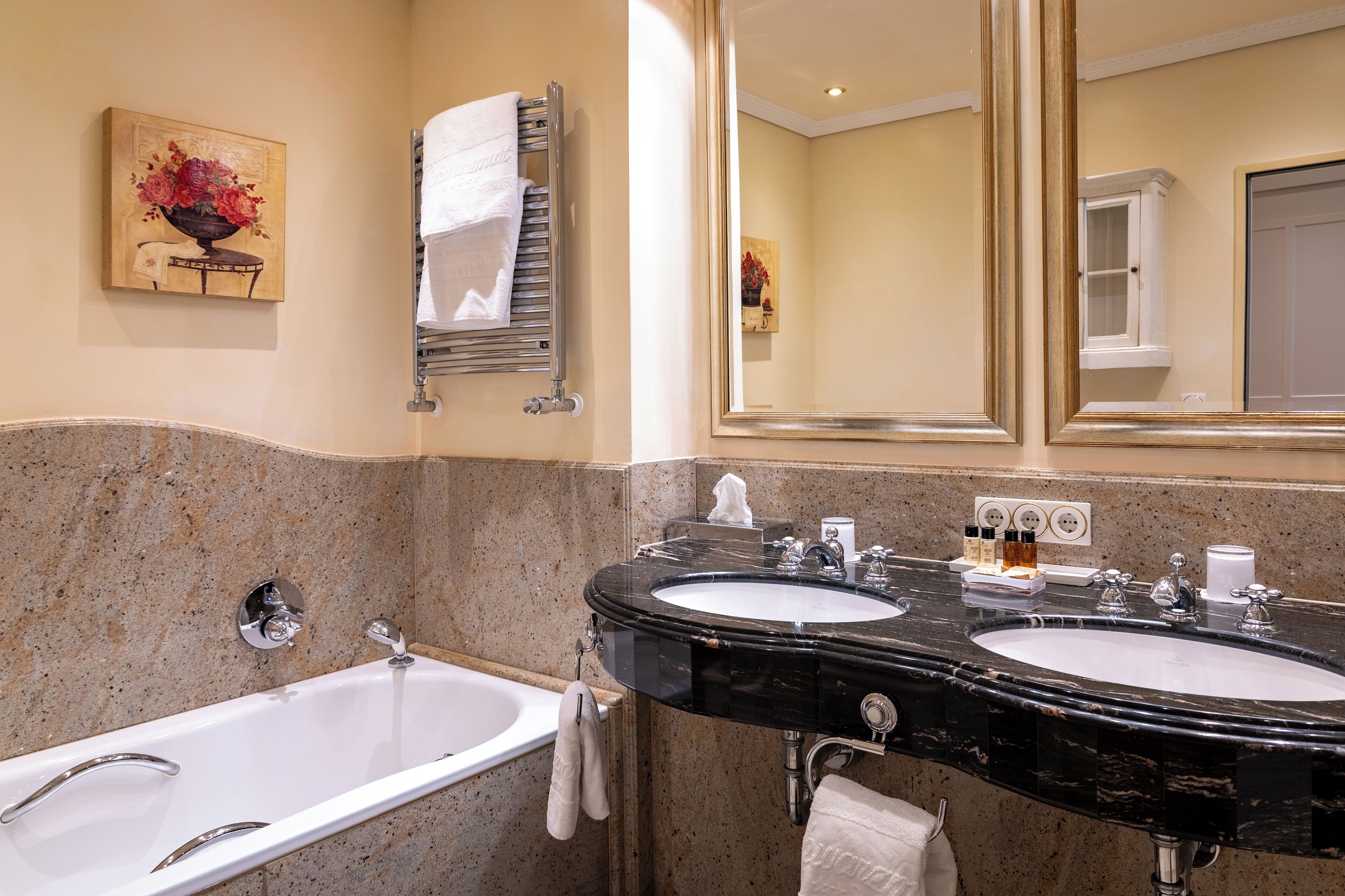 A bathroom with two sinks, a bathtub, and a large mirror.