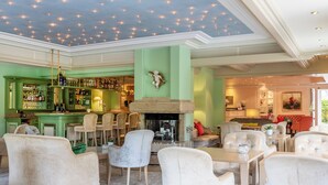 A spacious lounge with a bar area, comfortable seating, and a decorative ceiling. - Relais & Châteaux Hotel Schwarzmatt (Badenweiler)