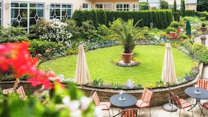 A courtyard with a lawn, potted plants, and outdoor seating. - Relais & Châteaux Hotel Schwarzmatt (Badenweiler)