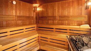 A sauna with wooden benches and a stone heating element.