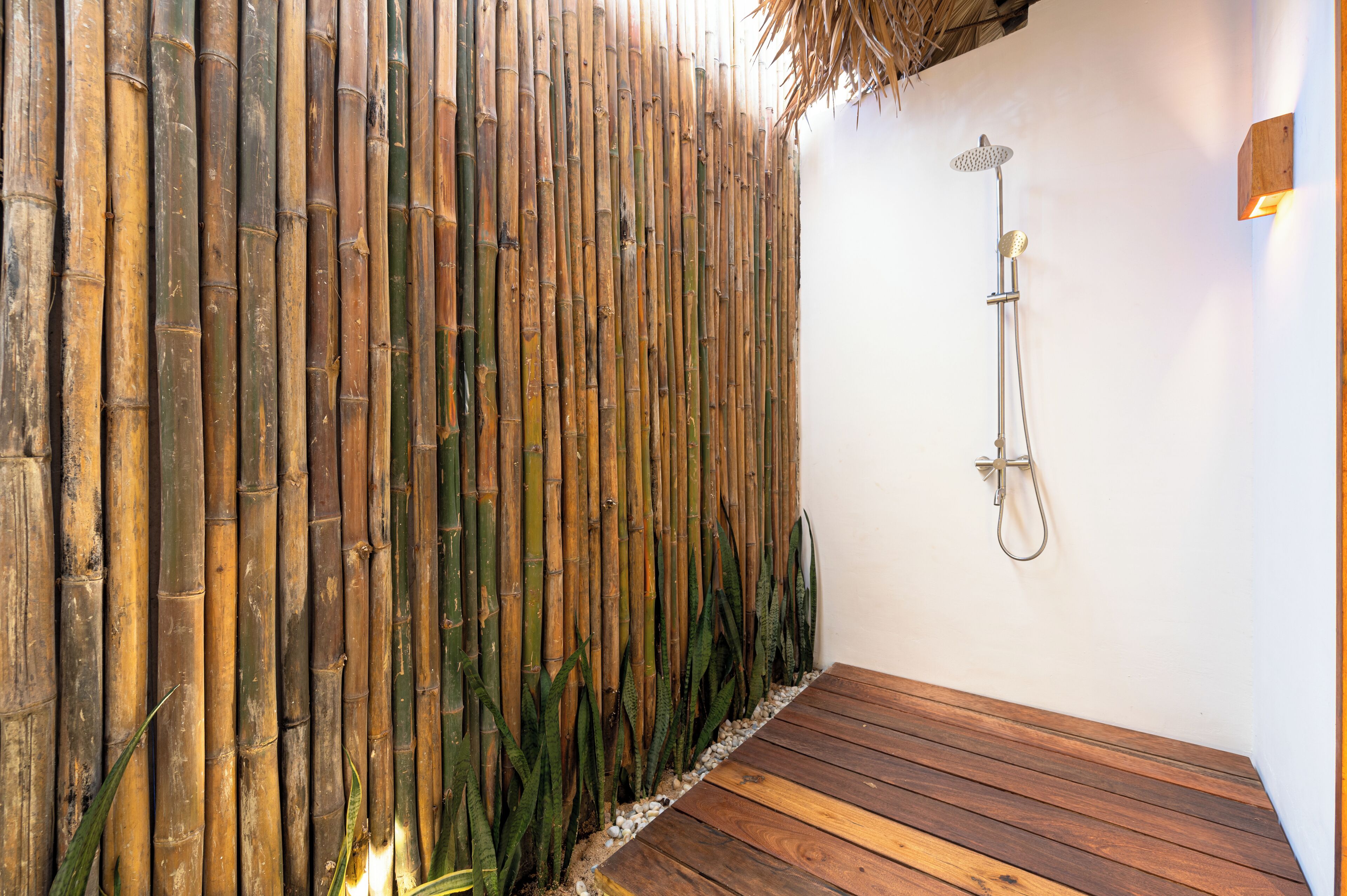 Un mur en bambou avec une douche et une plateforme en bois.