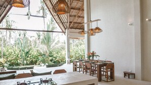 A spacious kitchen with a large island, wooden cabinets, and hanging wicker light fixtures.