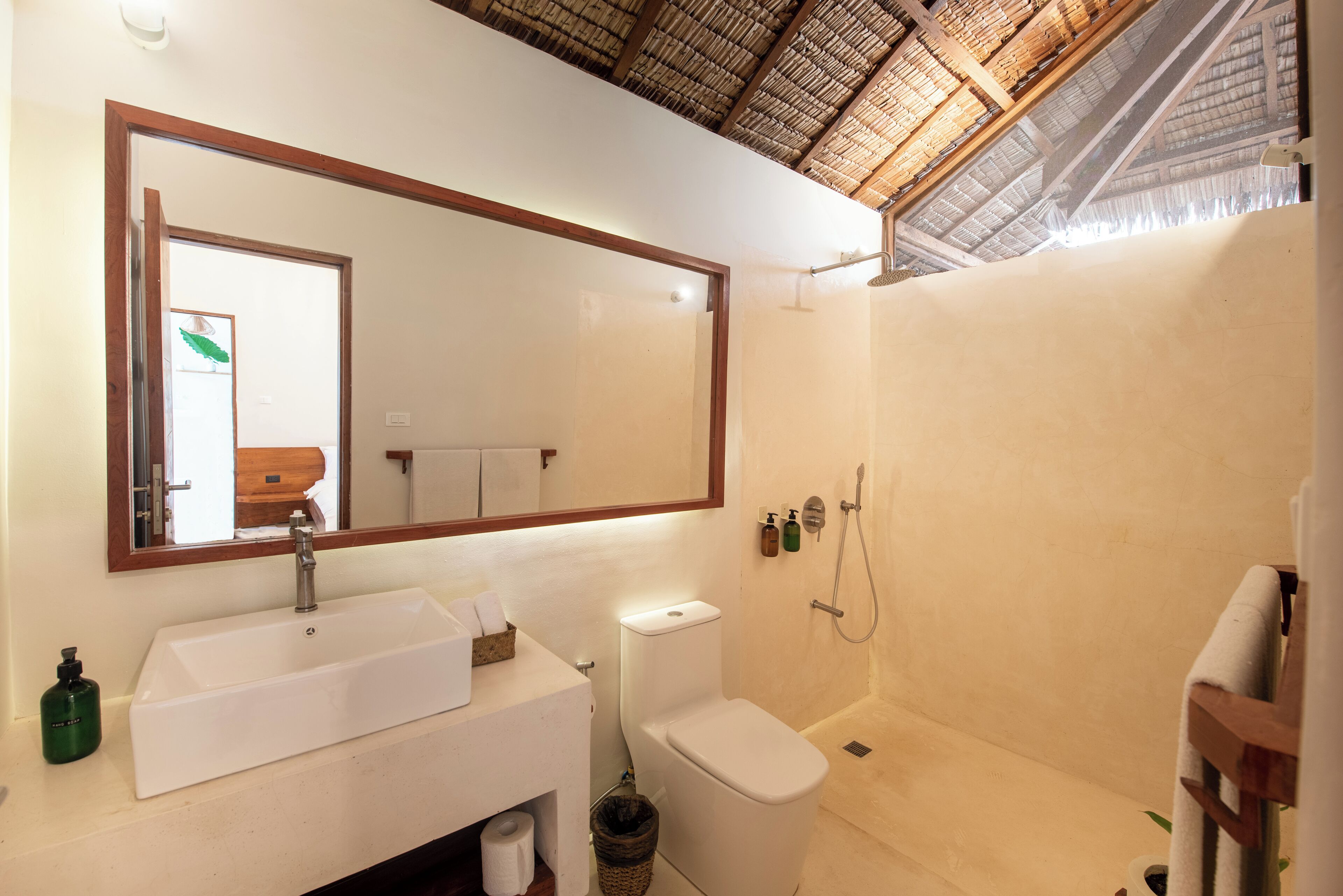 A bathroom with a large mirror, a sink, a toilet, and a shower.