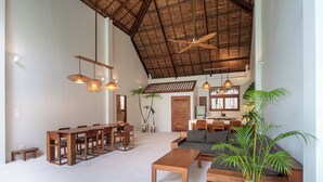 A spacious living area with a high ceiling, wooden furniture, and a large plant.