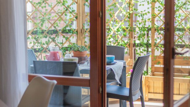 An outdoor patio with wicker furniture, a table with a blue bowl, and potted plants. - HOUSE OF SONJA (Viterbo)