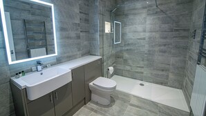 Un bagno moderno con uno specchio grande, un lavandino bianco, un WC e una cabina doccia in vetro.