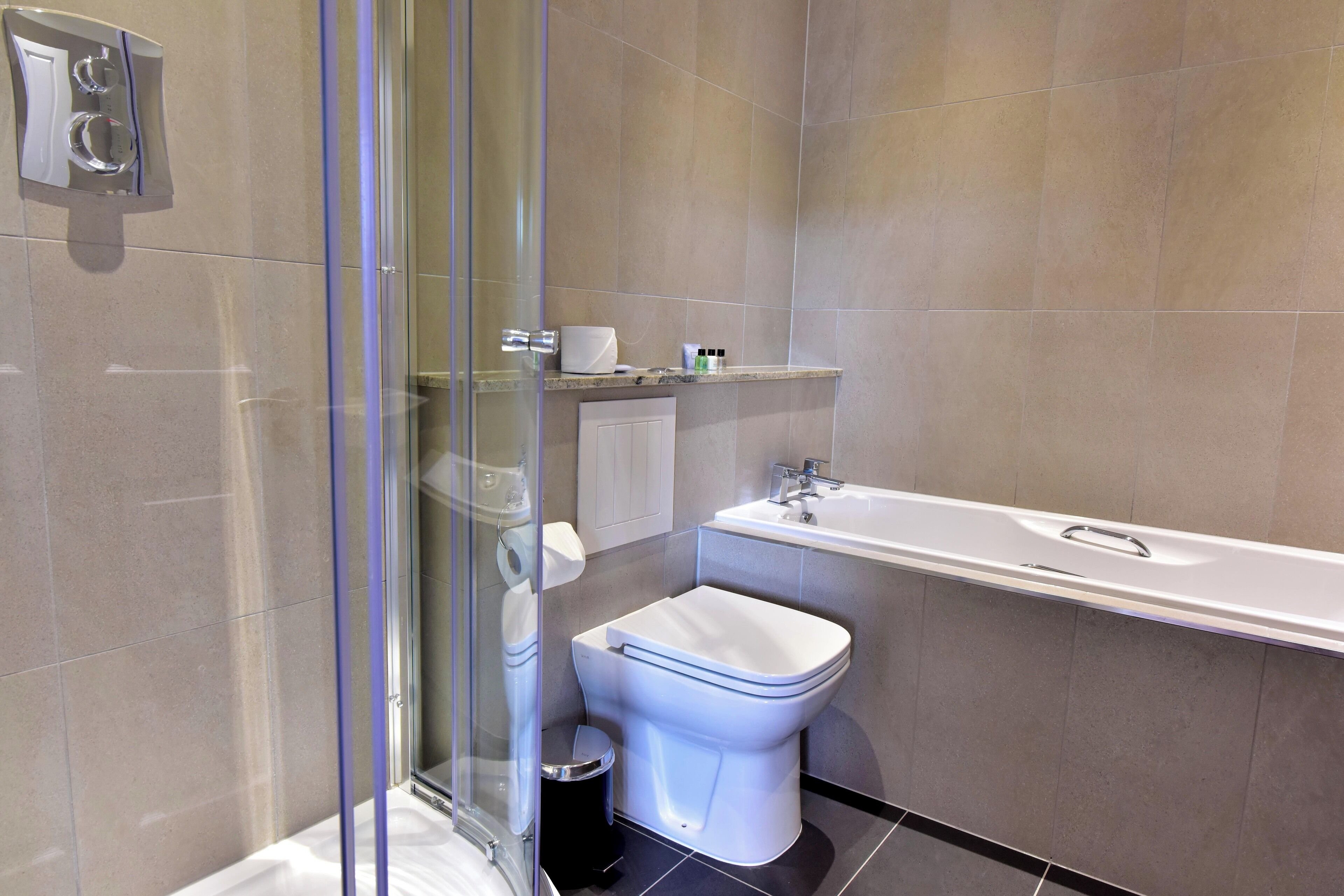 Une salle de bain moderne avec une douche à parois de verre, des toilettes et une baignoire.