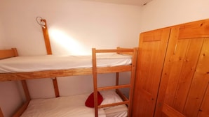 Ein Schlafraum mit Etagenbetten, Holzwänden und einem Kleiderschrank.