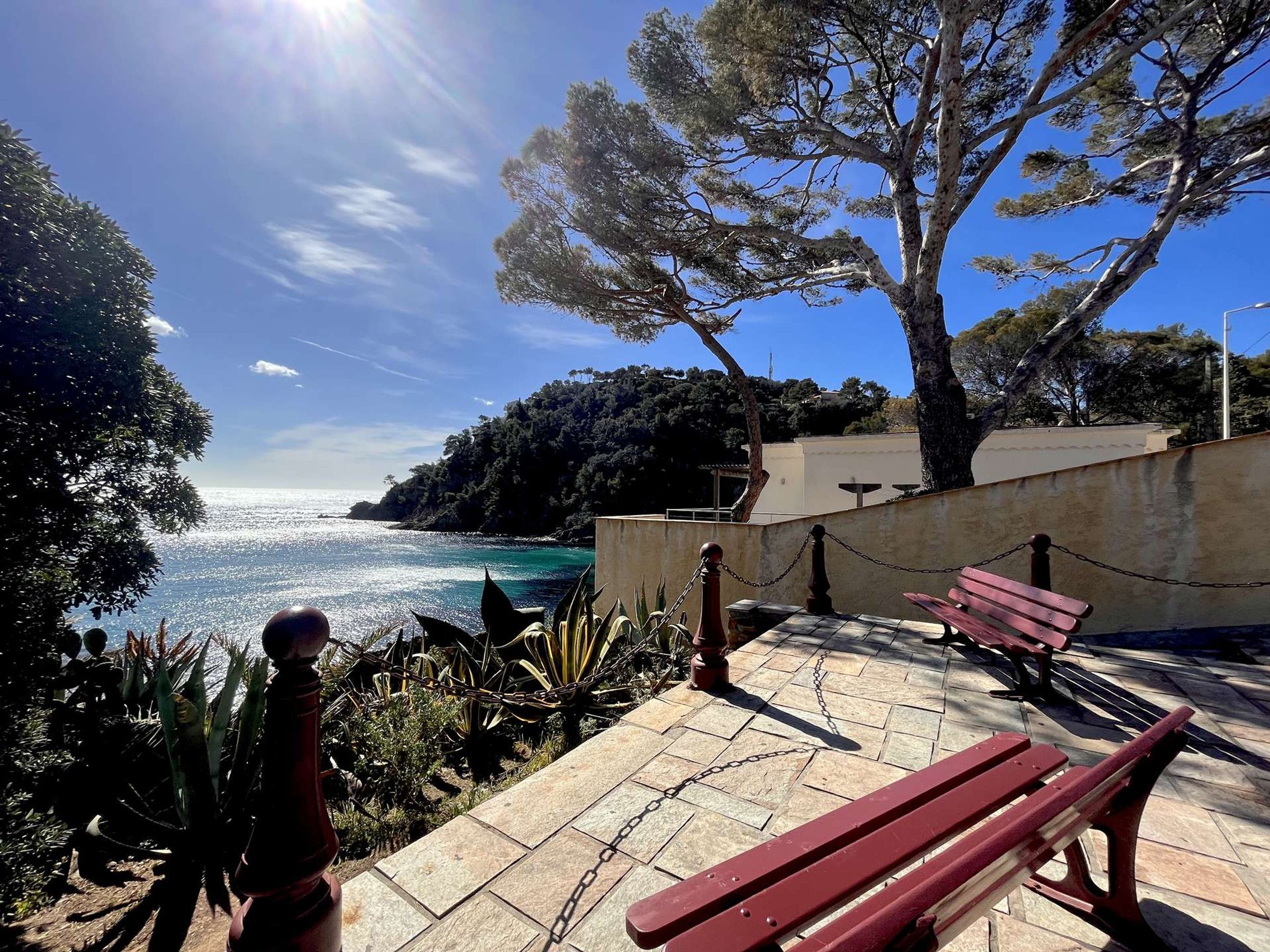 Une promenade en bord de mer, agrémentée de bancs, d’une clôture en treillis métallique et offrant une vue sur la mer.