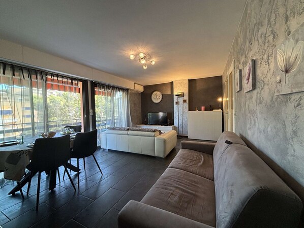 A modern living room with a sofa, dining area, and a TV.