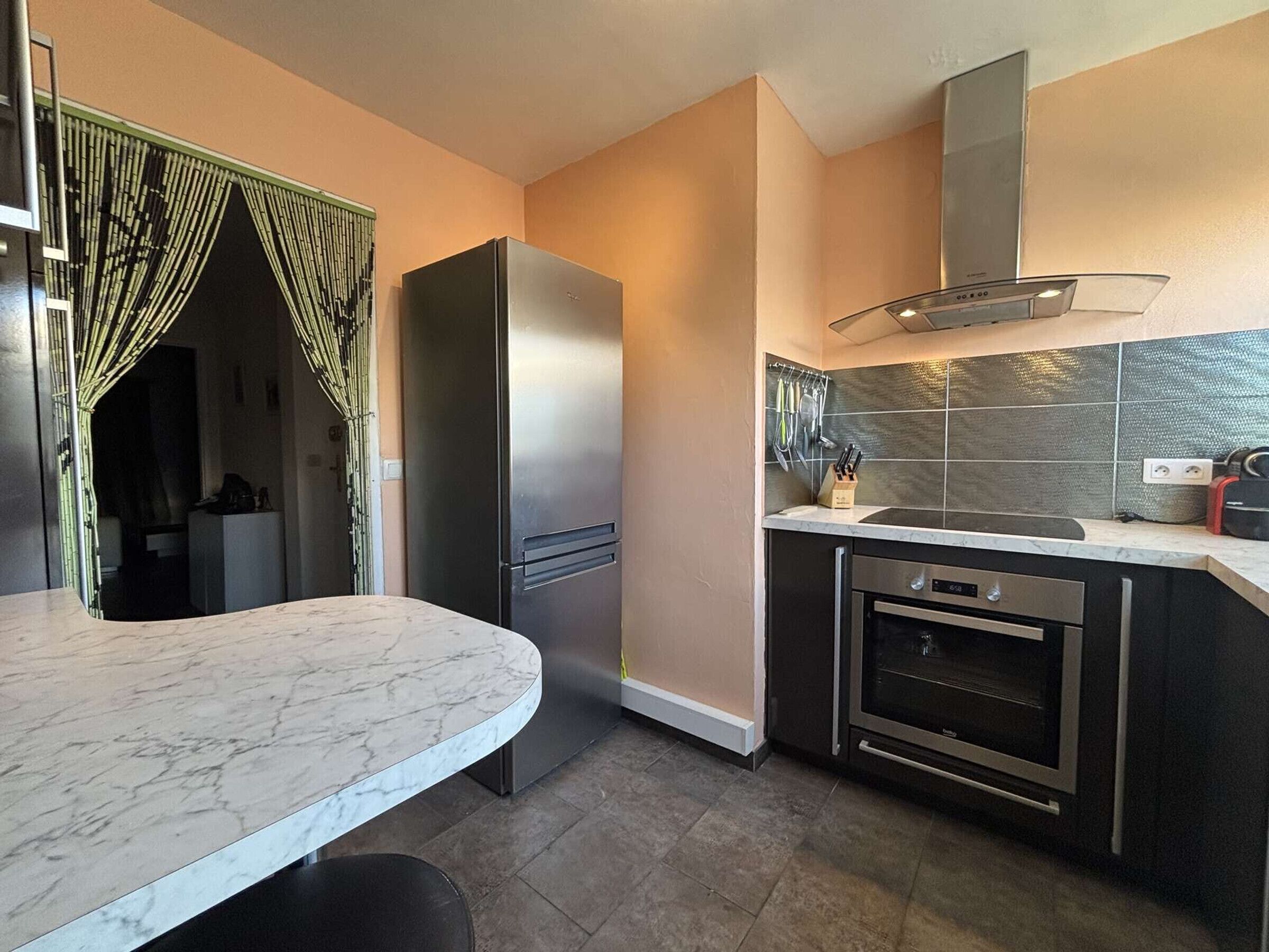 A modern kitchen with a marble countertop, stainless steel appliances, and a tiled backsplash.