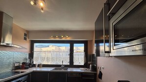 A modern kitchen with a large window, stainless steel appliances, and a marble countertop. - 2-room apartment with air conditioning in Cavalaire-sur-Mer (Cavalaire-sur-Mer)