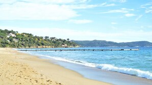 A beach with a wooden pier extending into calm waters, surrounded by greenery and houses. - 2-room apartment with air conditioning in Cavalaire-sur-Mer (Cavalaire-sur-Mer)