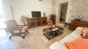 Een woonkamer met een bank, fauteuil, salontafel en een televisie op een houten kast.