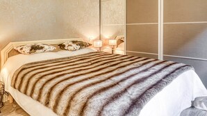 Une chambre à coucher avec un lit, une table de chevet, une lampe et un mur recouvert d’un papier peint à motifs.