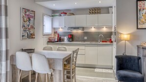 Une cuisine compacte avec un coin repas, une petite chaise noire et une table avec quatre chaises.