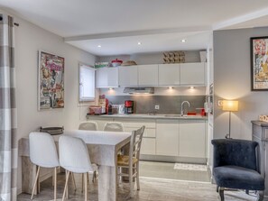 Een kleine keuken met een eethoek, een zwarte stoel en een tafel met vier stoelen.