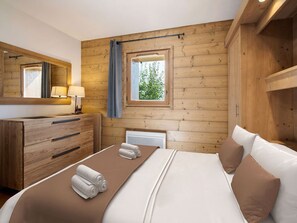 Una habitación de cabaña de madera con una cama, un tocador, un espejo y una ventana.
