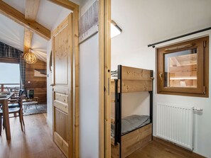 A wooden interior with a bunk bed, a dining area with chairs and a table, and a window with a view of the outdoors. - 2-bedroom cabin apartment for 6 with garage in Les Saisies (Les Saisies)