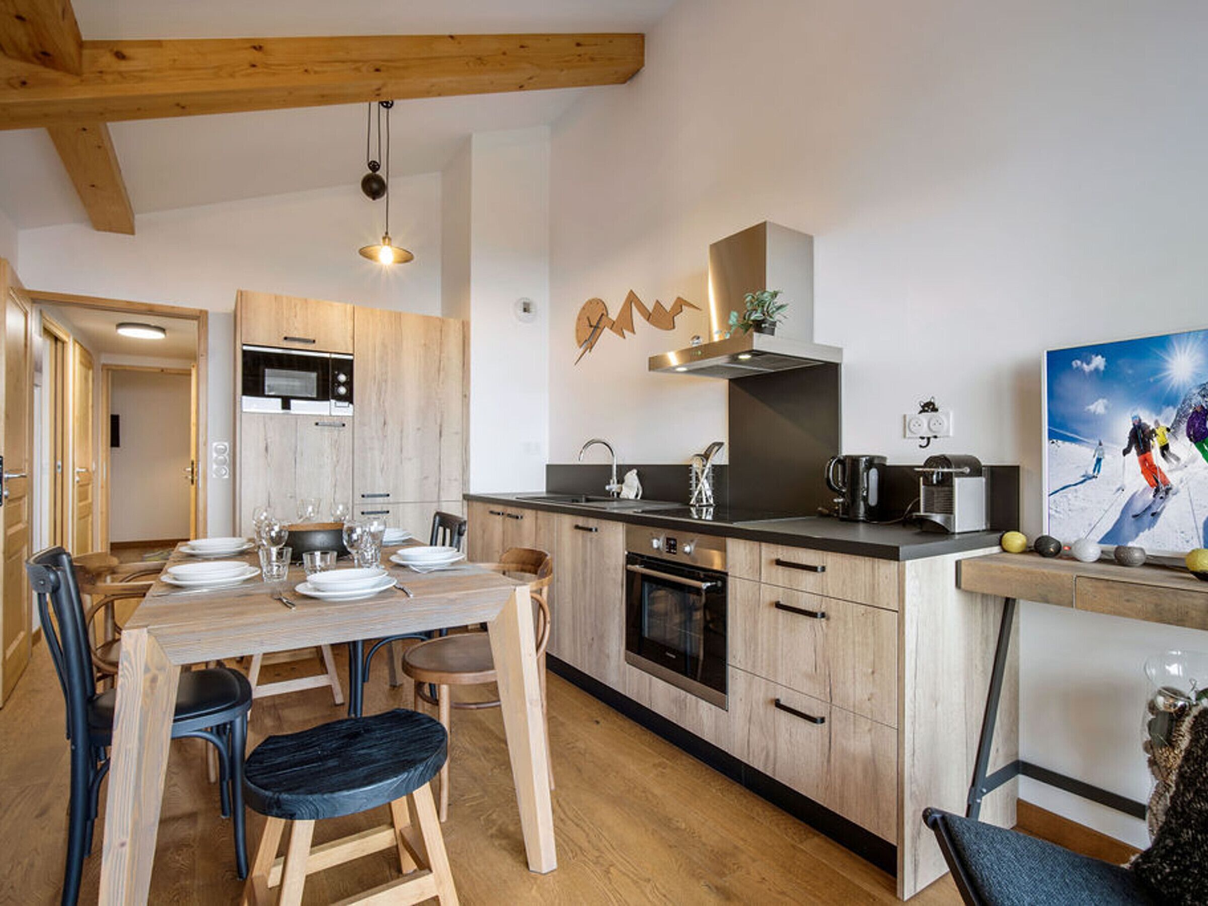 A modern kitchen with wooden cabinets, a built-in oven, and a dining area with a wooden table and chairs.