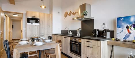 A modern kitchen with wooden cabinets, a built-in oven, and a dining area with a wooden table and chairs.