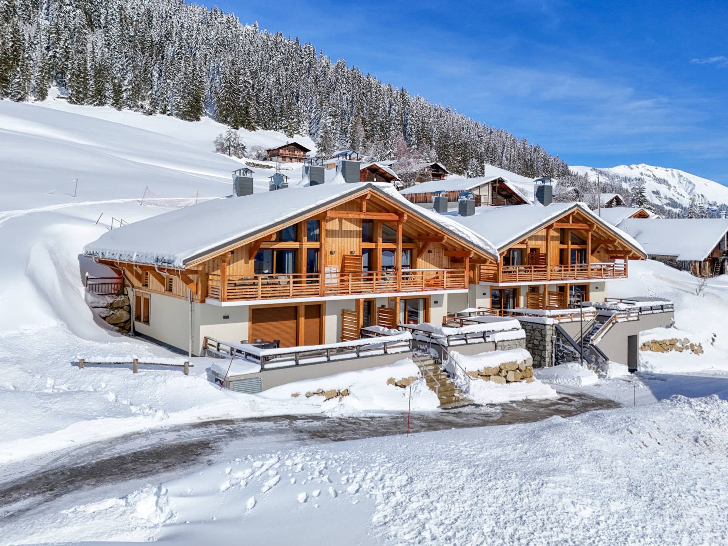 Un hotel de estilo chalé con varios balcones de madera, base de piedra y un paisaje montañoso nevado.