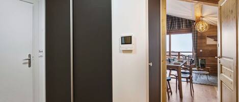 A modern interior with a sliding door, a dining area with wooden furniture, and a visible thermostat on the wall.