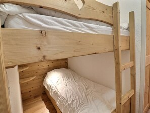 A bunk bed with a wooden frame and white bedding.