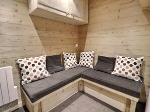 A corner seating area with a wooden bench and polka-dotted cushions.